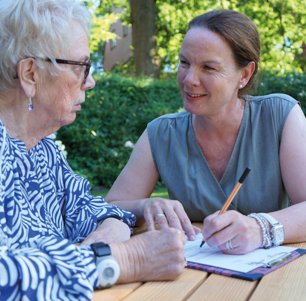 Anne Heitkämper Qualifizierte Senioren-Assistenz im Gespräch mit einer Seniorin beim Ausfüllen eines Formulars